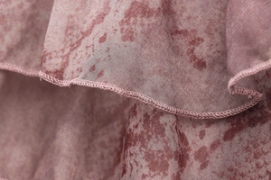 Detailed view of pink floral chiffon fabric featuring ruffled edges and fine stitching