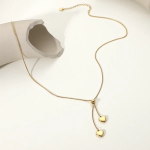 Dettaglio della collana a Y placcata oro 14K con due ciondoli a cuore e perla scorrevole