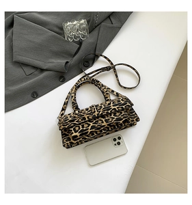 Leopard print crossbody bag shown with grey blazer and smartphone for size scale
