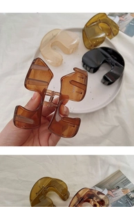 Detailed close-up of large minimalist hair claws in amber, black, and beige colors
