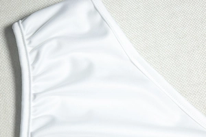 Nahaufnahme des weißen Kleides mit gerafftem Stoff, eleganten Falten und feiner Textur