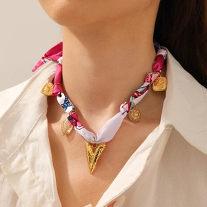 Close-up of elegant silk scarf necklace with leopard print and gold heart pendant charms