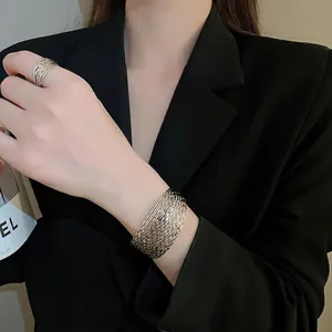 Minimalist silver multi-layer metal bracelet and ring set worn on a black blazer sleeve