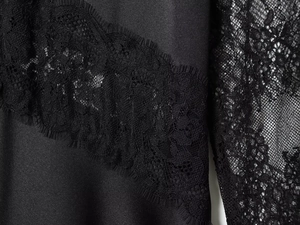 Detailed view of elegant black satin fabric with intricate lace trim stitching