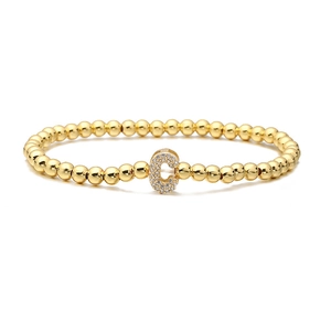 Detail of gold beaded elastic bracelet featuring a micro-paved letter C charm with zircon