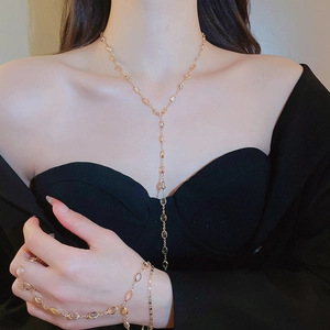 Detail of a gold Y-shaped necklace and matching bracelet set with faceted clear beads