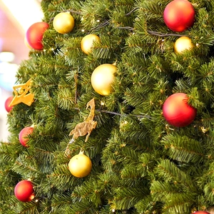 Close-up of red and gold Christmas balls and reindeer ornaments on pine tree branches