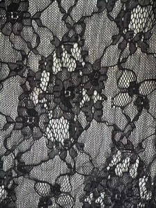 Macro view of delicate black lace fabric with intricate floral patterns and mesh details