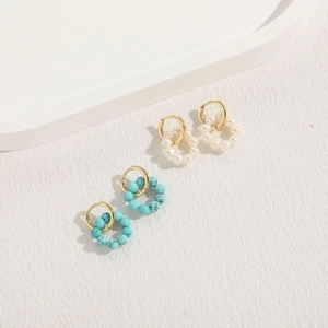 Detailed shot of gold earrings with white pearls and sky blue turquoise stone beads