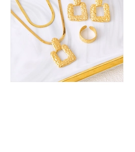 Golden jewelry set with textured square necklace, earrings and ring on marble tray