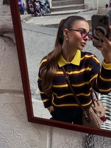 Detail of navy, yellow and red striped polo knit sweater with long sleeves and collar