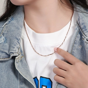 Detail of rose gold twisted snake chain necklace on neck showing texture and drape