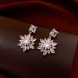 Detailed view of 14k gold plated snowflake earrings with zircon on a leather jewelry box