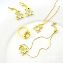 Flat lay of a gold bear jewelry set with necklace earrings and ring on a white plate