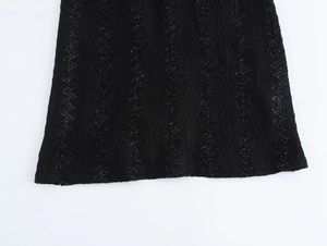 Close-up of black fabric with elegant wavy glitter patterns and textured detail