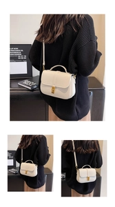 Detail of white lychee grain leather saddle bag with gold metal buckle and shoulder strap