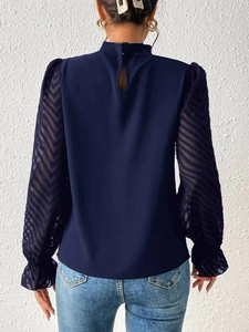 Detail of navy mock neck top featuring chevron chiffon sleeves and keyhole back