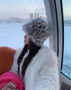 Close-up of leopard print faux fur bucket hat and white fluffy coat in winter setting