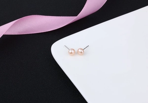 Detailed macro shot of round light pink freshwater pearl earrings with silver studs
