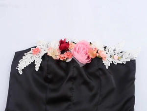 Detail eines schwarzen Bandeau-Tops mit 3D-Stoffrosen in Pink und Rot sowie weißer Spitze