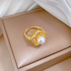 Detail of gold flower ring with center white pearl and sparkling zircon crystal edges