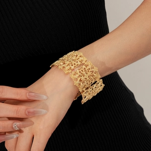 Detailed view of wide gold cuff bracelet featuring intricate floral filigree patterns