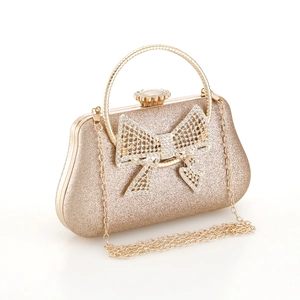 Detailed view of luxury gold evening clutch with rhinestone bow and metal handle