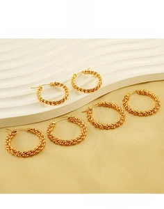 Macro detail of twisted golden titanium steel hoop earrings with textured finish