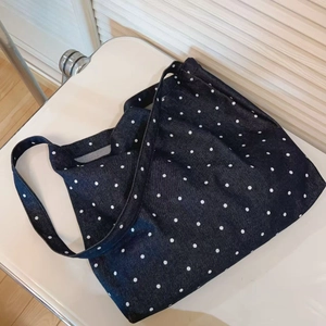 Detail of large capacity denim tote bag with white polka dots and wide shoulder strap