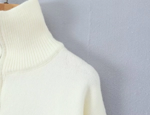 Close-up of white ribbed knit collar and soft fabric texture on a stand-up zip cardigan