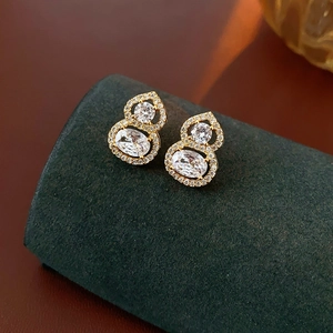 Macro shot of gold-plated gourd earrings with sparkling zircon crystals on velvet