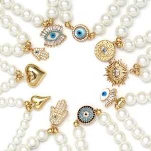 Multi-piece set of pearl bracelets with gold Evil Eye and Hamsa Hand charms