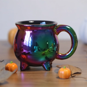 Rainbow plated ceramic witch cauldron coffee mug on wooden table with Halloween decor