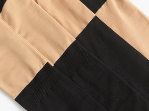 Detail of beige and black patchwork tights with ribbed texture and smooth knit finish