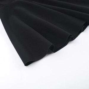 Gros plan sur l'ourlet de la robe moulante noire montrant les coutures et le drapé