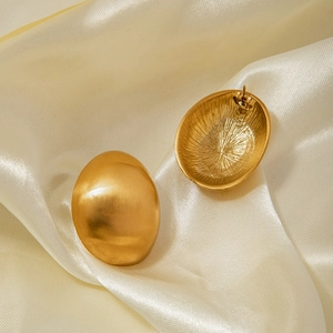 Macro shot of oval gold stainless steel earrings with matte brushed metal texture