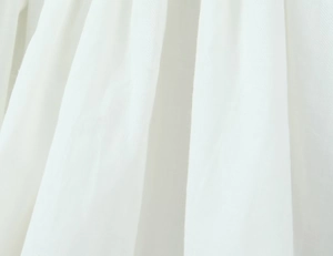 Detailed macro view of white cotton-linen fabric texture with natural vertical drapes