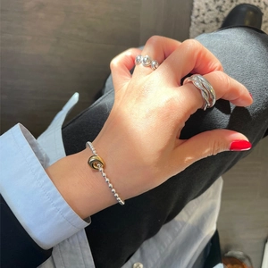 Detailed view of mixed metal jewelry featuring silver bead bracelet and spiral gold pendant