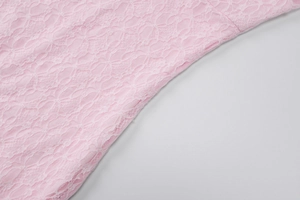 Close-up of the delicate pink lace texture and intricate floral pattern on the evening dress