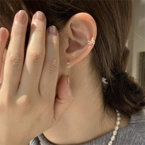 Close-up of minimalist square zircon stud earring and dual-band ear cuff on person