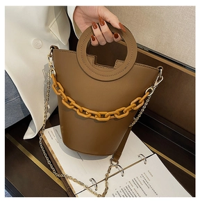 Close-up of brown bucket bag featuring amber resin chain and circular handle detail