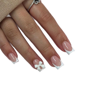 Long square French press-on nails with nude pink base and white 3D bow accent