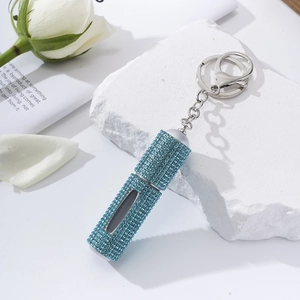 Macro detail of a rhinestone-encrusted portable perfume bottle with blue crystals