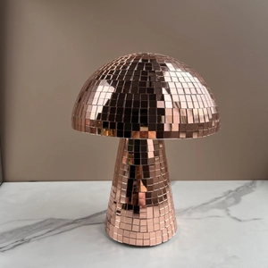 Macro shot of rose gold disco ball mushroom decor reflecting light on marble surface
