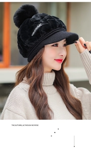Close-up of black plush winter hat with ear flaps, pom-poms and GIRLSPEAK embroidery