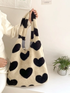 Close-up of white plush heart tote bag with soft faux fur texture shown by a model