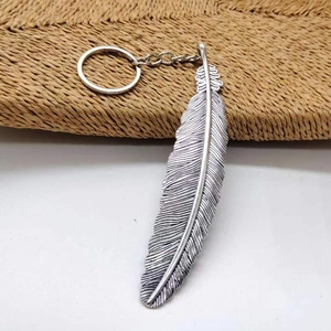 Detailed macro view of vintage silver alloy feather keychain on a textured background