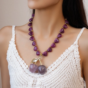 Detailed close-up of a purple acrylic heart cherry pendant necklace with gold leaf detailing