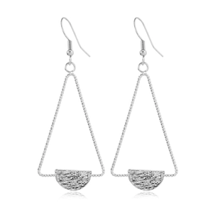 Macro detail of geometric silver earrings with hollow triangles and textured moon charms
