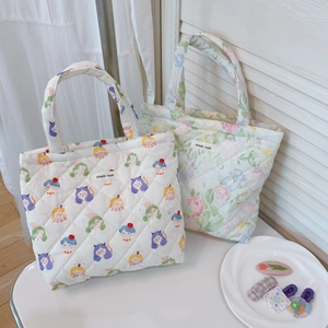 Detail of floral and cartoon quilted tote bags with simple wish label on white wood background